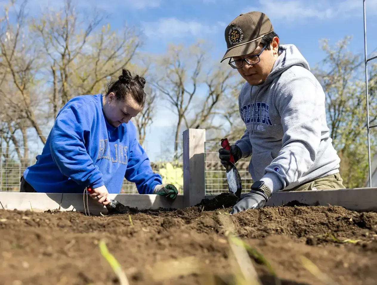 Two students working outside in garden area.