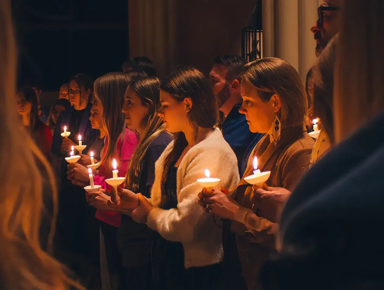 Students together in worship holding candles.