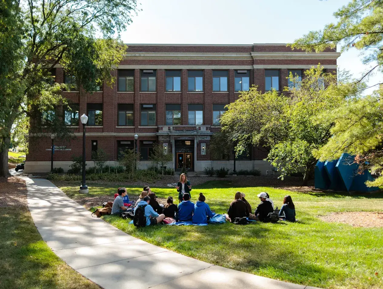 Students sitting in grassy area on campus.