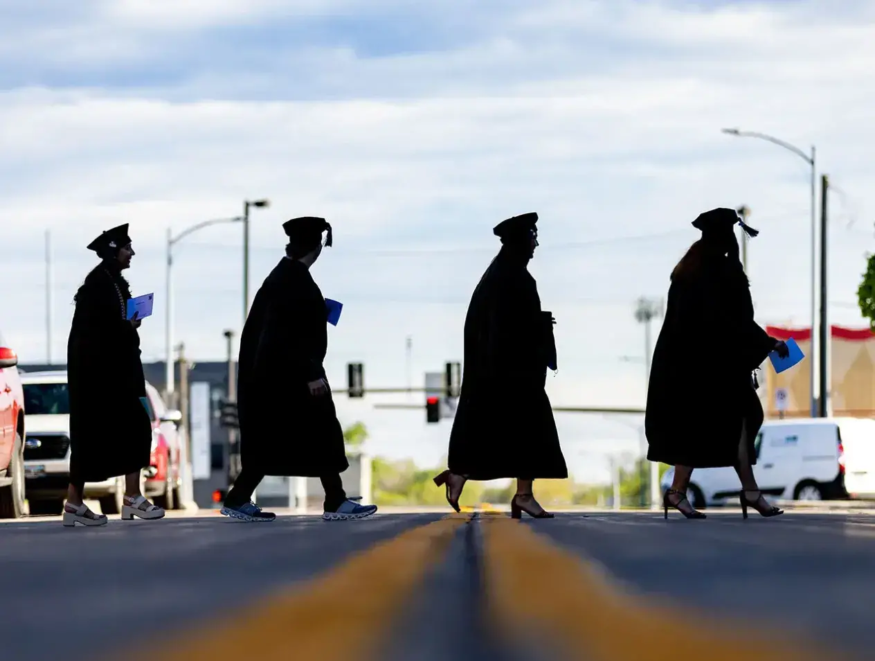 Four individuals in regalia crossing a street