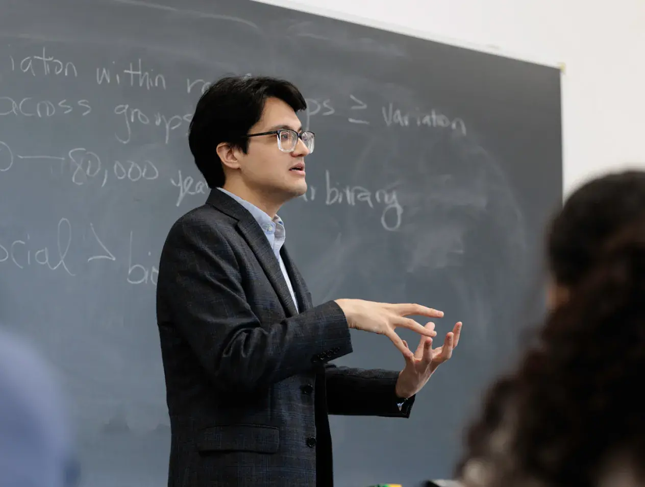 Male professor lecturing in front of a blackboard
