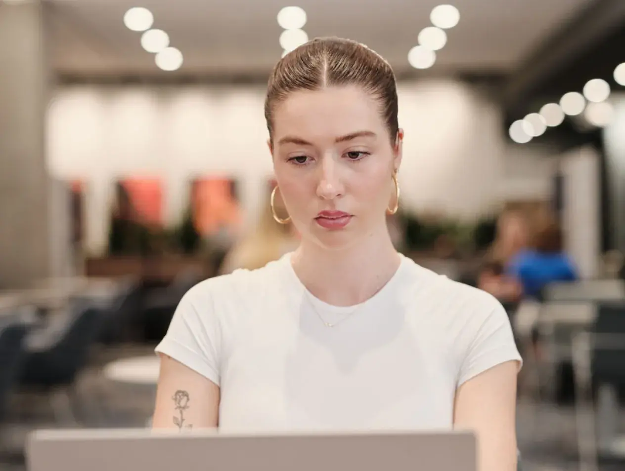 female student sitting at table reading laptop facing camera