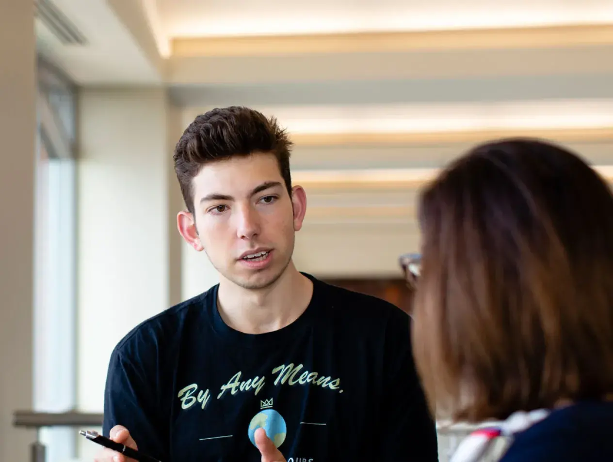 student talking at the top of the main staircase in the Harper Center