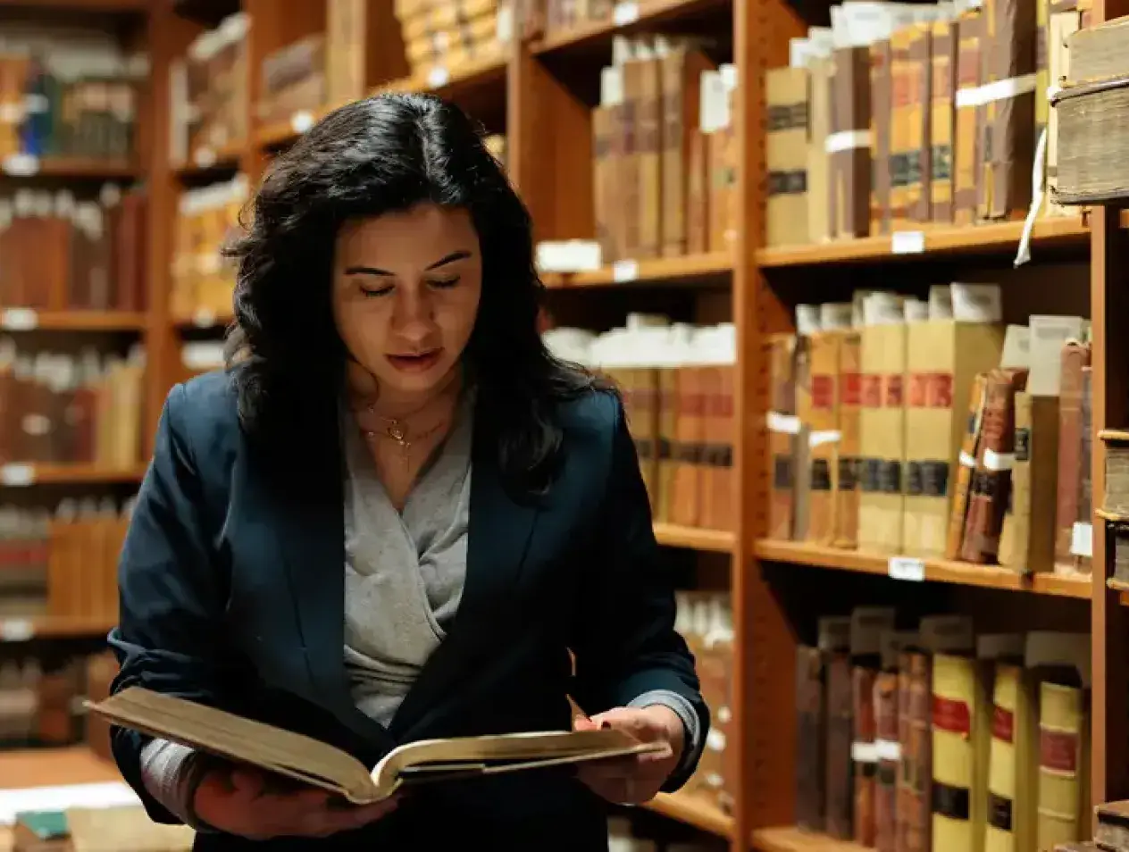 Woman reading book amidst the stacks.