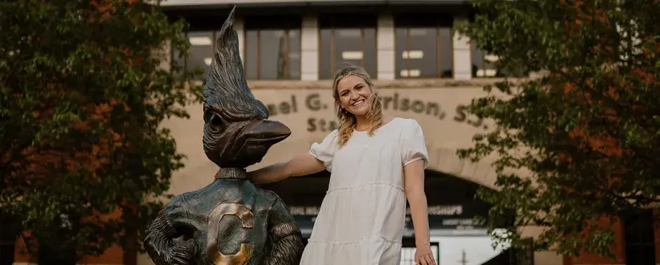 Clara Korensky posing on campus with Billy Bluejay statue