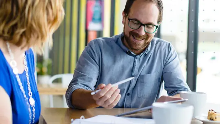 Two adults studying options at home table.