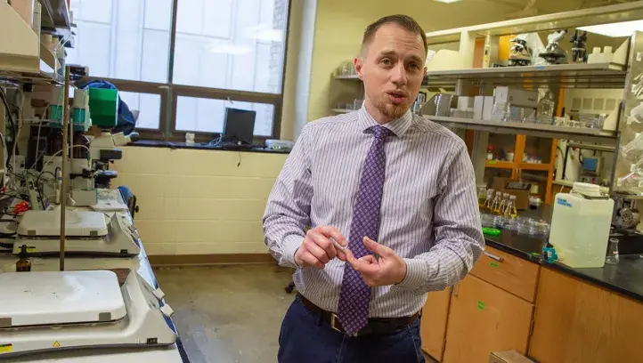 Eric Villa explaining his research in lab setting.