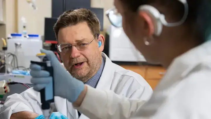 Peter Steyger collaborating with colleague in lab setting.