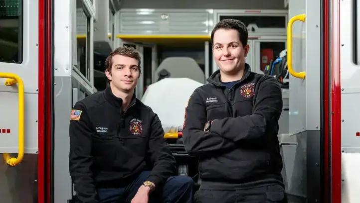 Paramedicine students posing at back of ambulance.