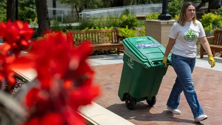 Student wheeling garbage barrel.