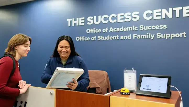 Student works with staff at Success Center desk.