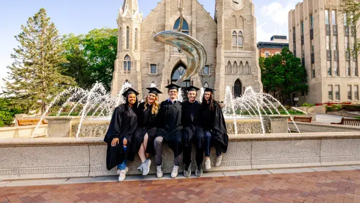 Graduating seniors posing in front of the fountain on Creighton's campus.
