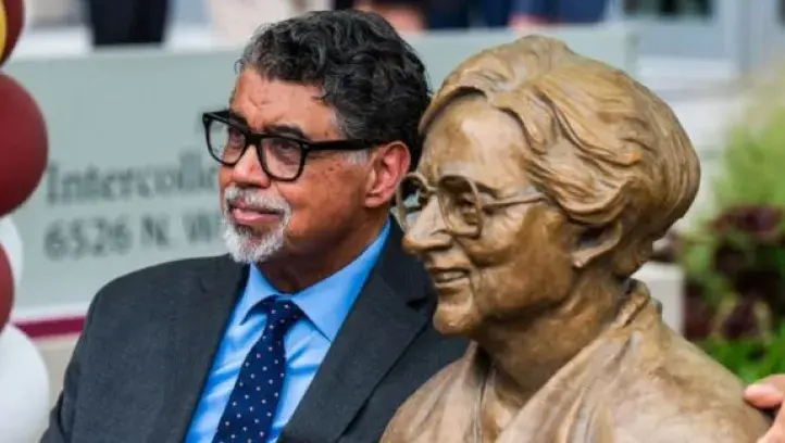 Littleton Alston sits next to a bronze statue of Sister Jean Dolores