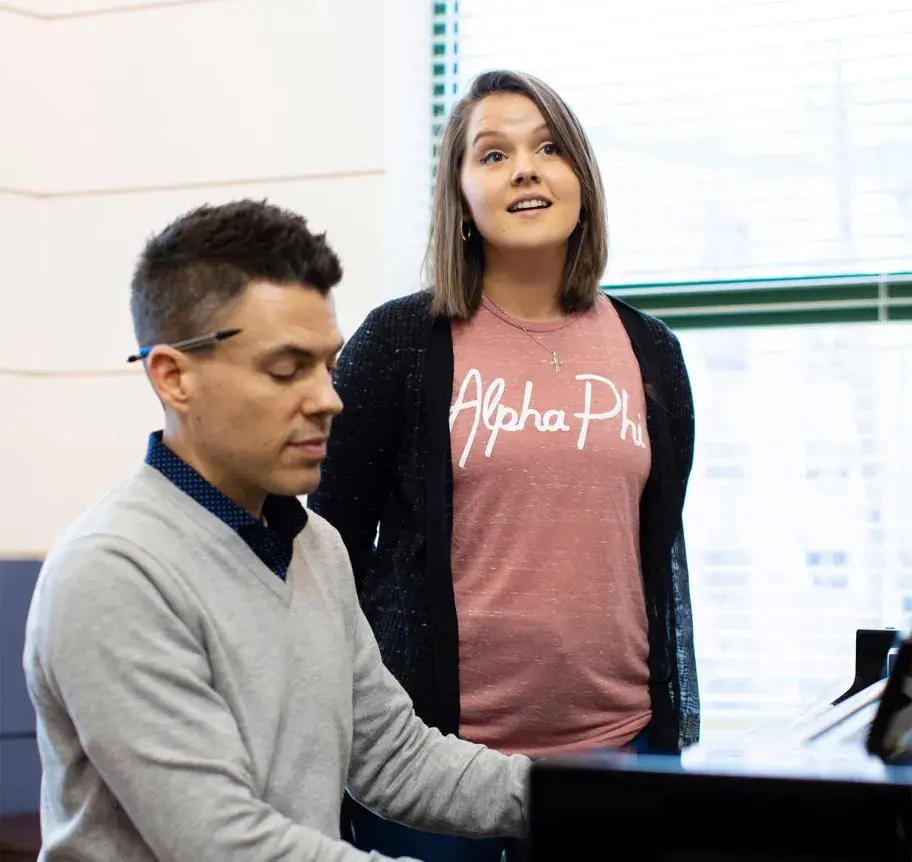 Faculty playing piano while student sings