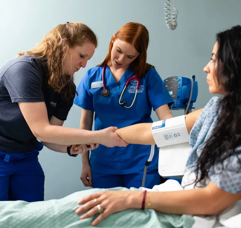 Nursing student and faculty member examining patient