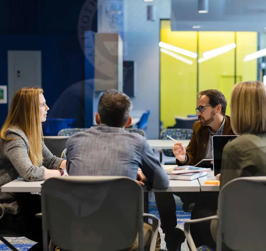 Students and faculty in meeting room around table