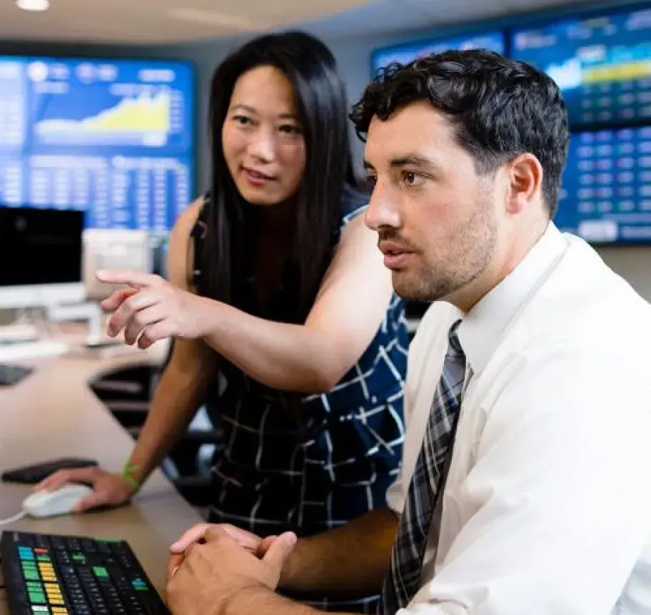 A woman pointing to a screen while having a discussion with a man