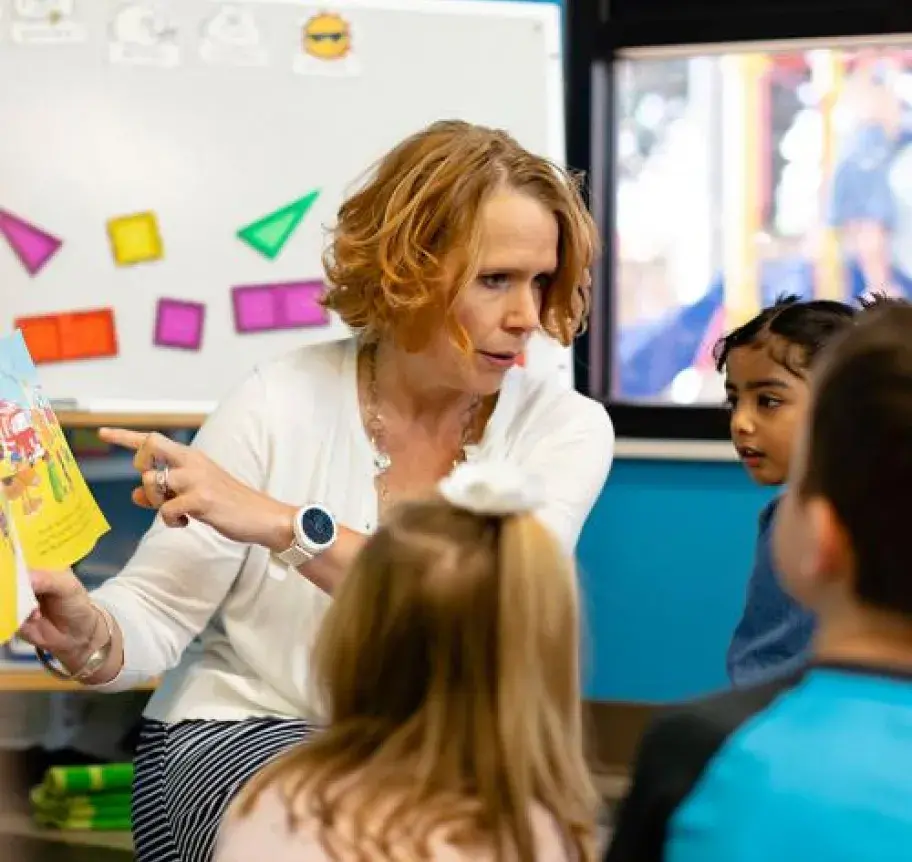 A teacher reading a book to a group of children
