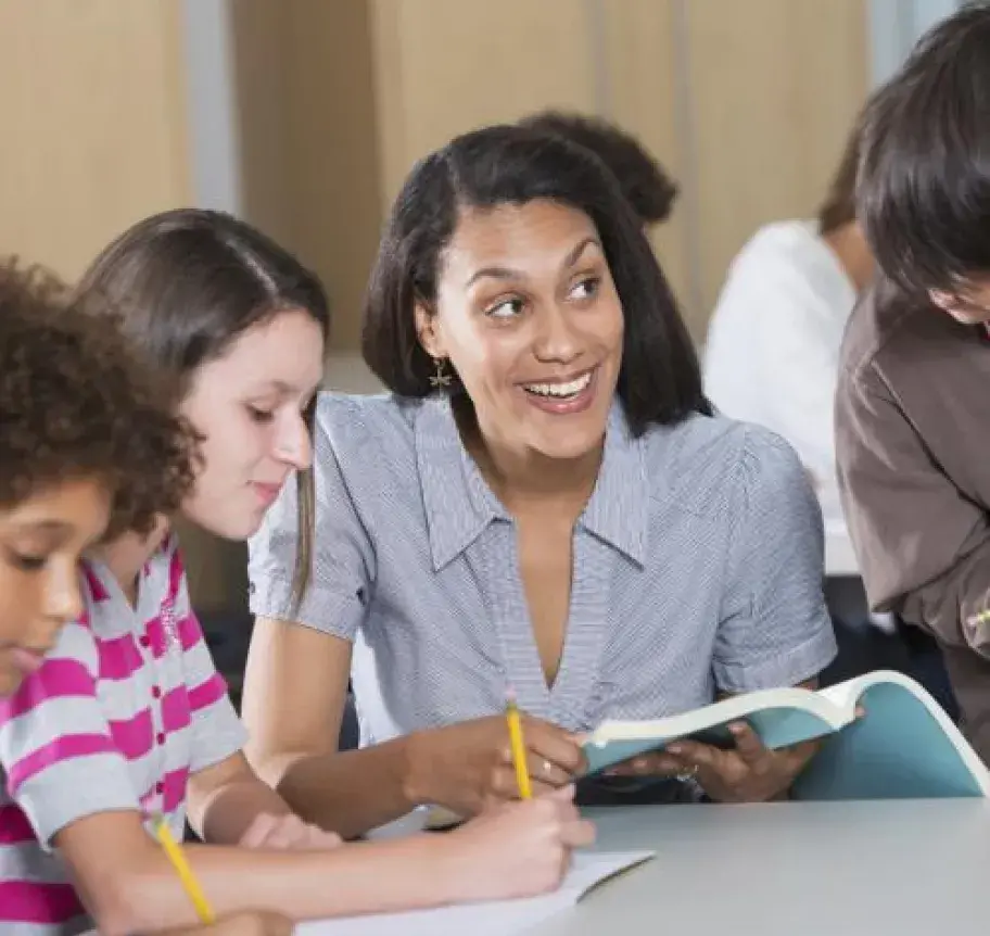 A teacher assists a group of students with coursework