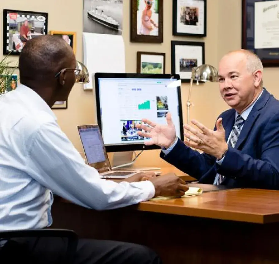 A financial investment manager advising a client who is seated across a desk from him
