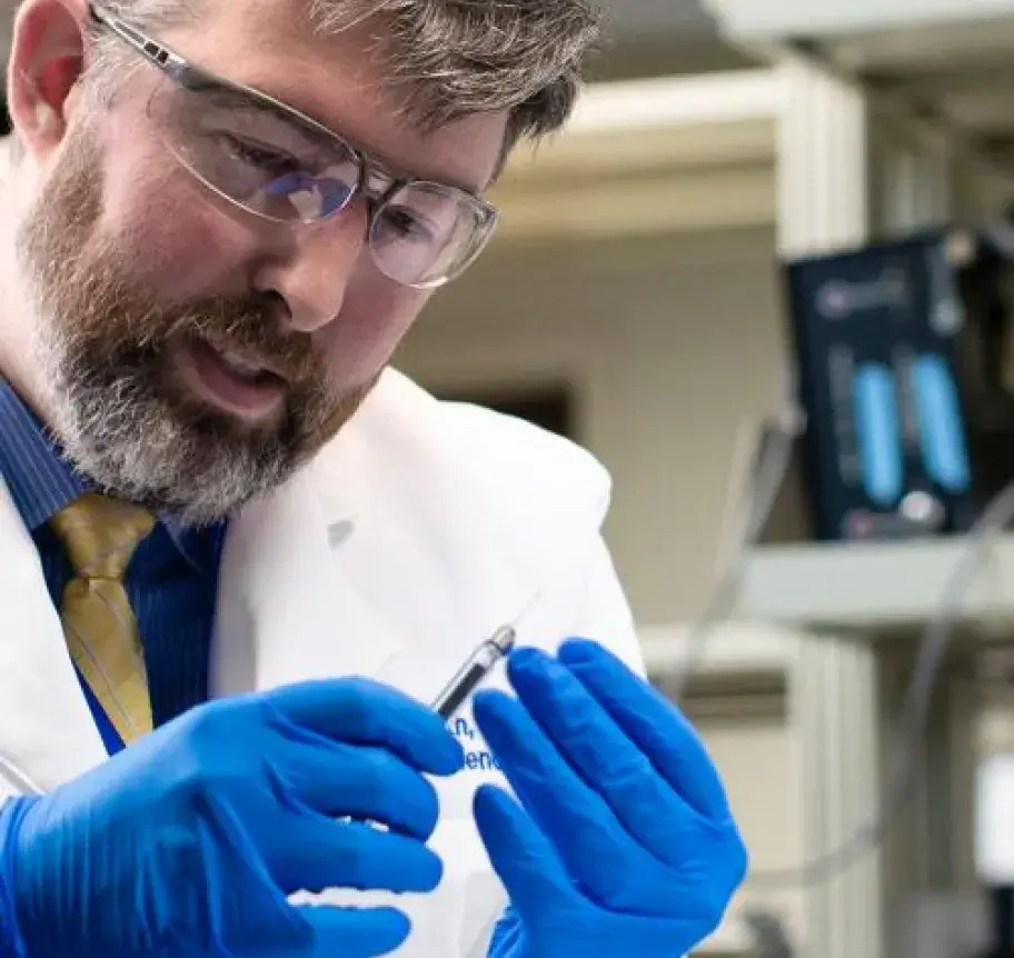 A scientist in a lab holding a filled syringe