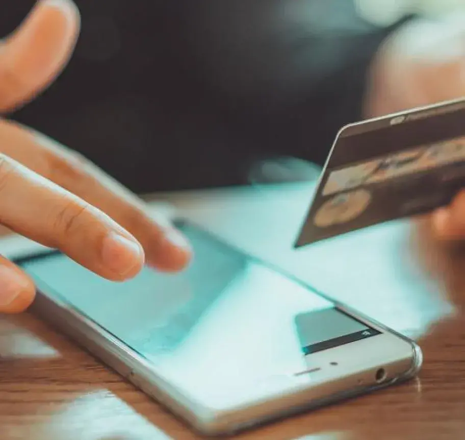 Closeup of a person holding a credit card while using a mobile device