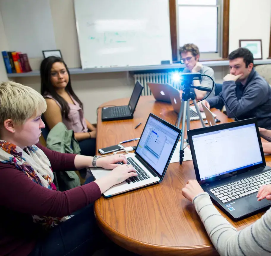 Faculty working with students around a table