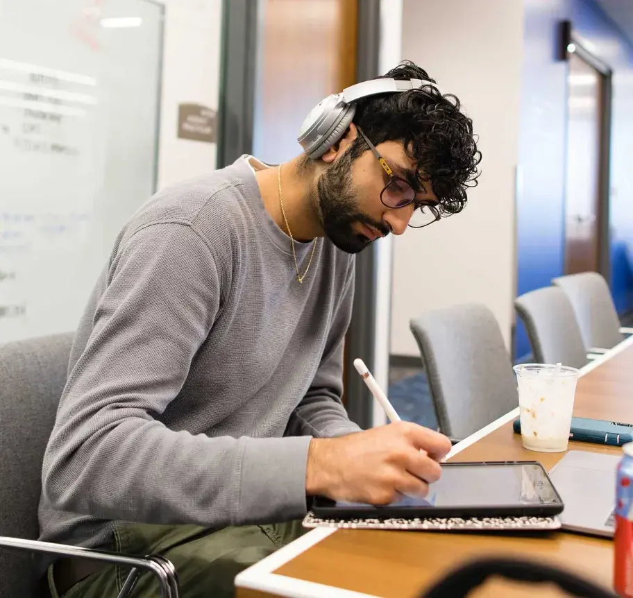 Student working on tablet with headphones on
