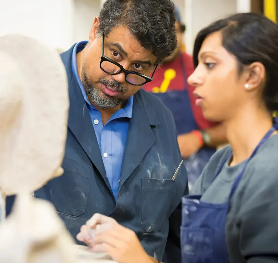 Faculty working closely with student on sculpture
