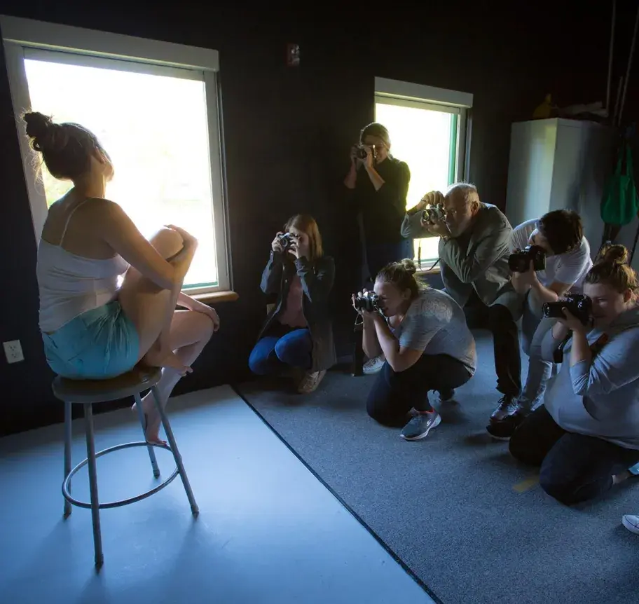 Students photographing a model on a stool in studio