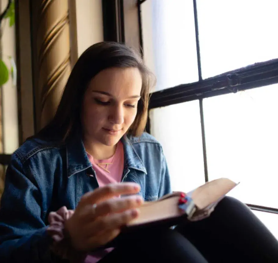 Student reading sitting by a window