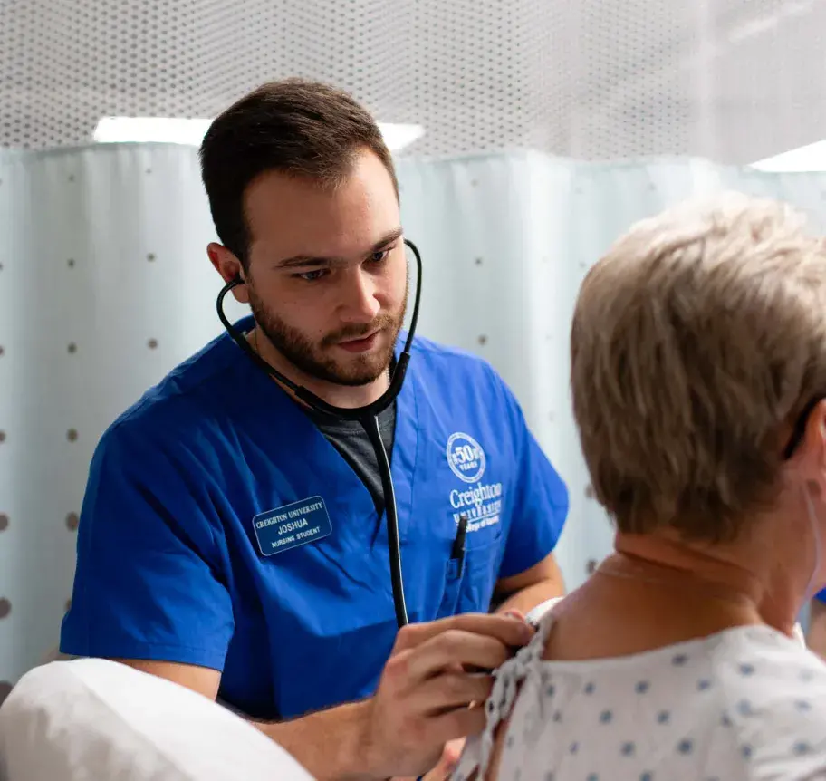Nursing student using stethascope on patient's back