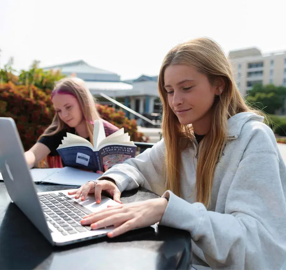 Students working together outdoors at table with laptops