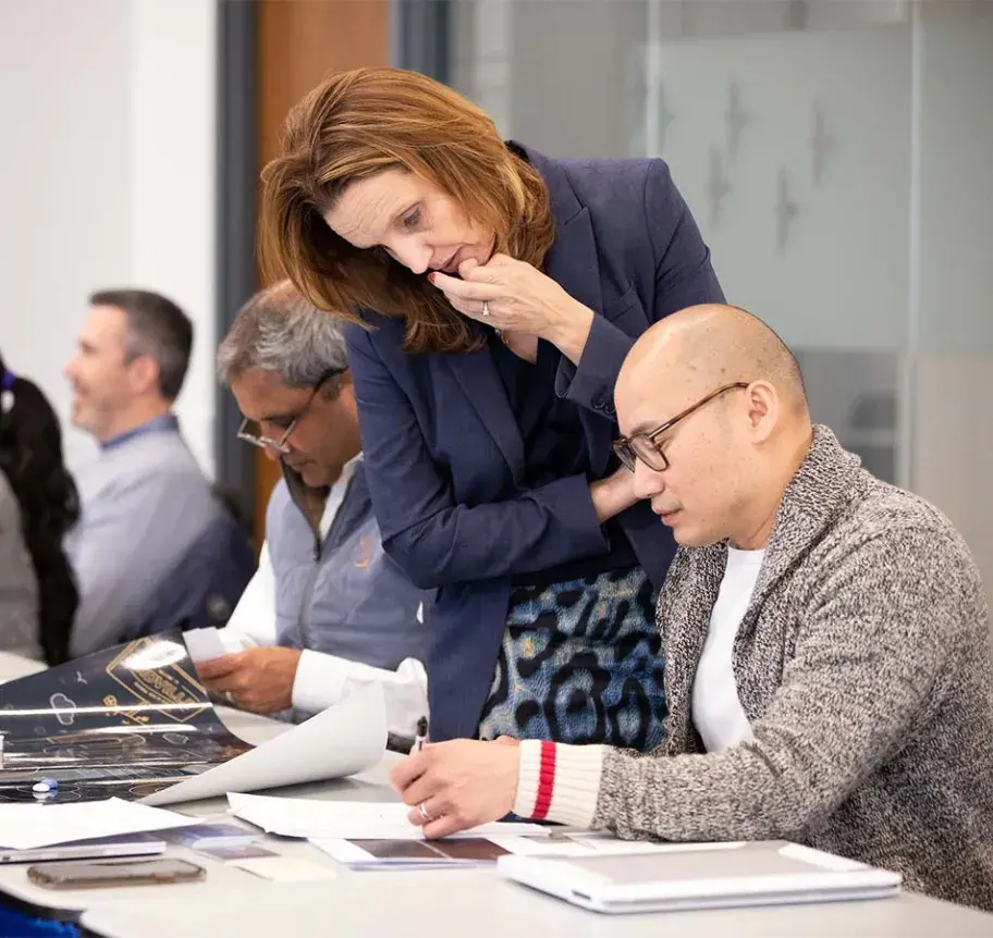 EMBA faculty working with student in classroom