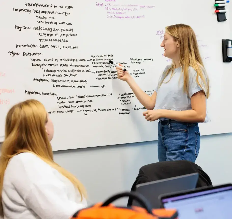Students at white board studying coursework.