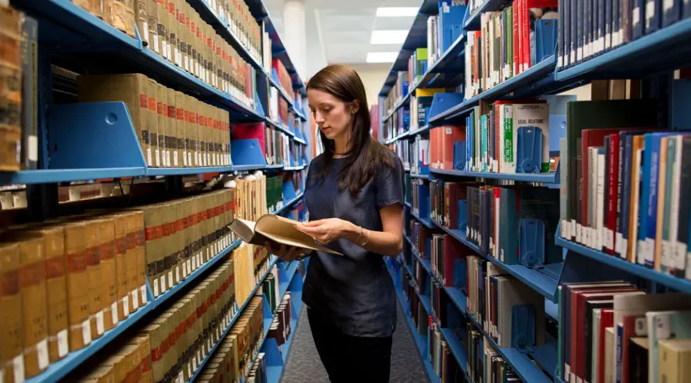 Student looking through books in the library