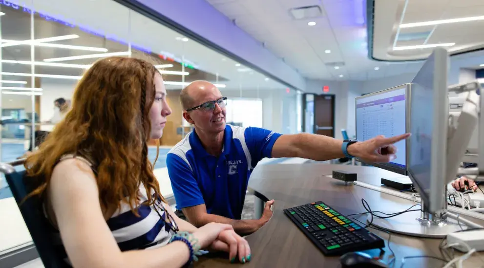 Professor pointing at screen while student watches