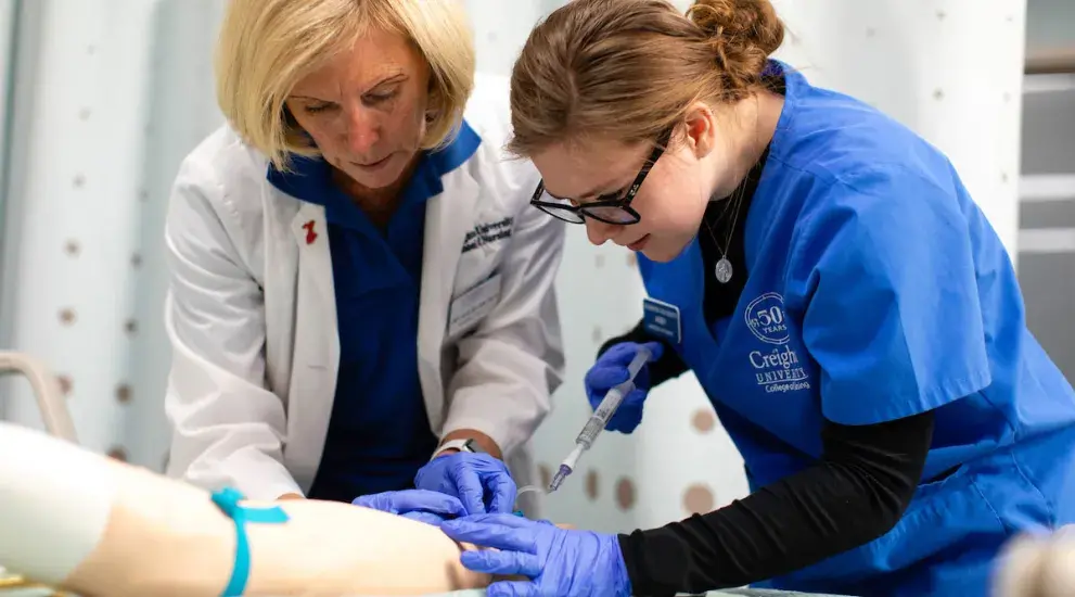 Nursing student practices injecting a maniken