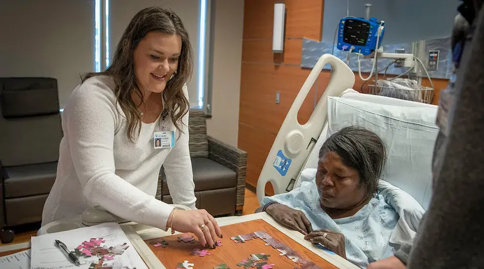 An occupational therapy student helping a patient put together a jigsaw puzzle