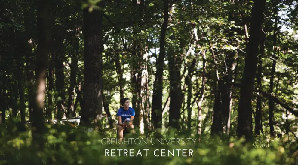 Video thumbnail showing a retreat participant sitting in the woods