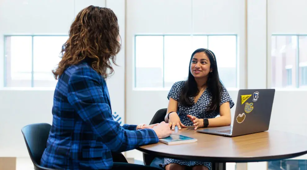 Student and faculty member talking at a table