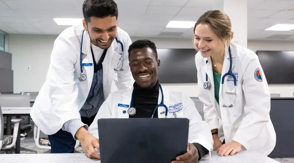 3 diverse students looking at a laptop