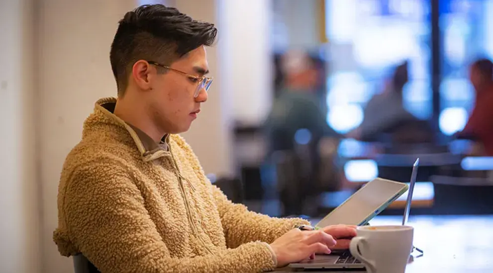 student on laptop sitting at a table