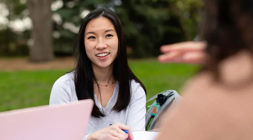 Two students sitting at table outdoors
