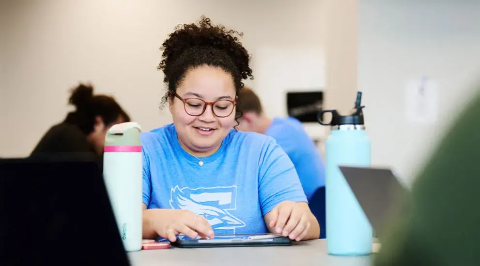 student on tablet sitting at a table