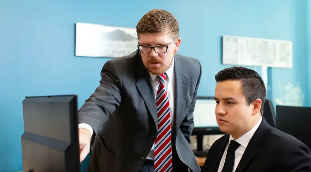 Two professionals examining data on computer.