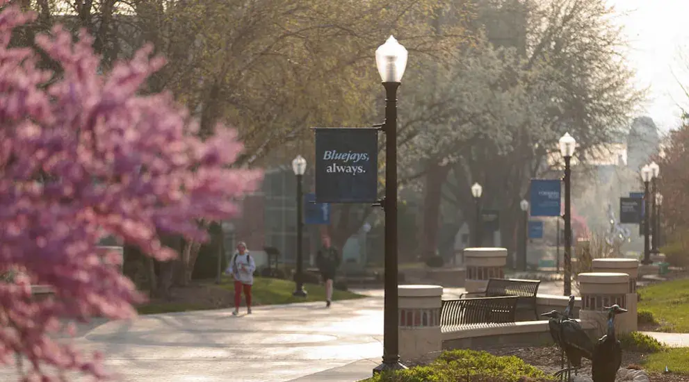Student walking on campus in bright morning sunshine.