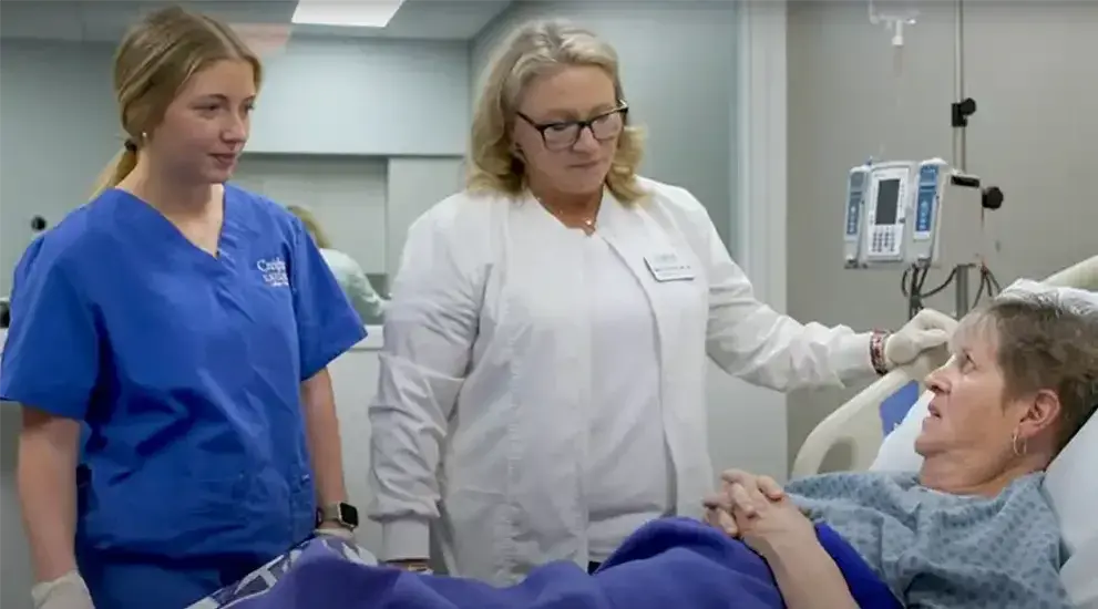 Student and teacher providing nursing care to patient.