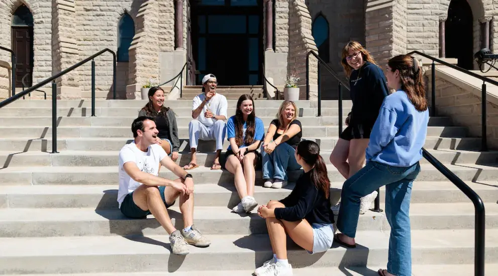 Group of students sitting on stairs talking.