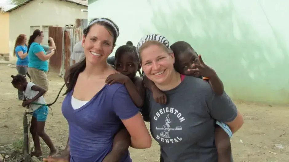 Female dental students in Africa posing with children